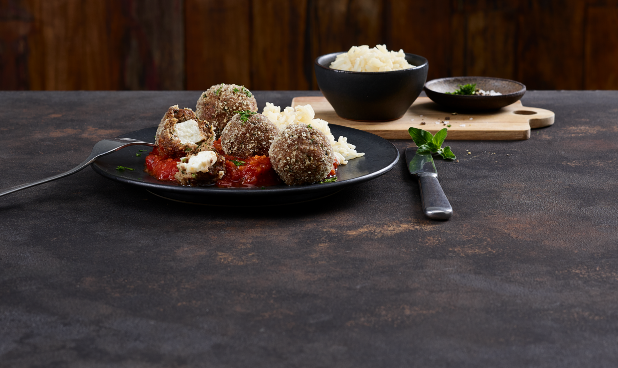 Hackbällchen auf einem Teller mit Feta und Tomatensauce