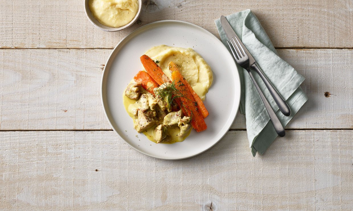 Teller mit Gitzi Ragout an Safran Sauce mit Kartoffelstock und Bundkarotten