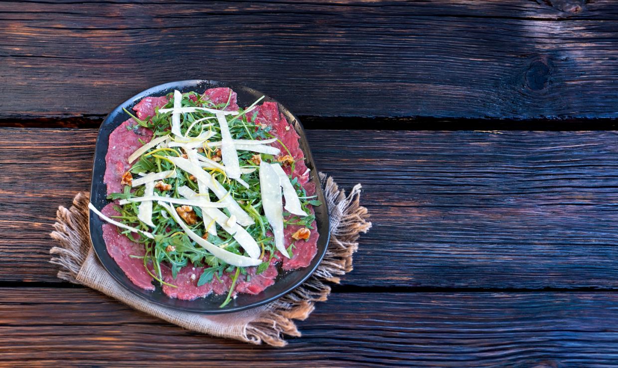 Carpaccio vom Schweizer Rind mit karamellisierten Baumnüssen, Parmesansplitter, Zitronenzesten und Rucola