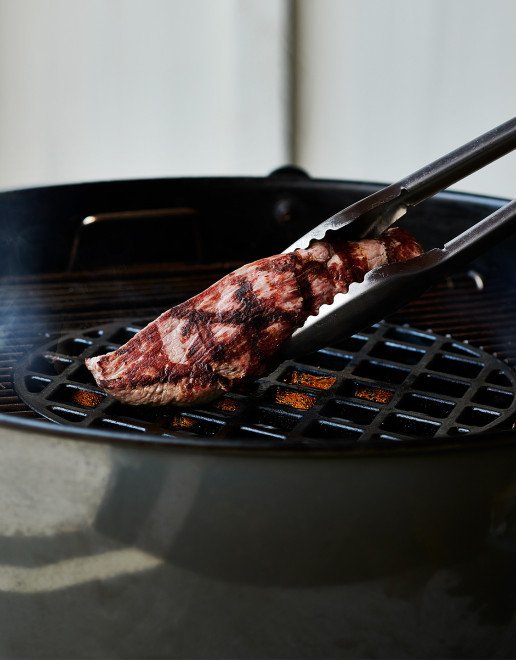 Fleischstück wird auf dem Grill gewendet