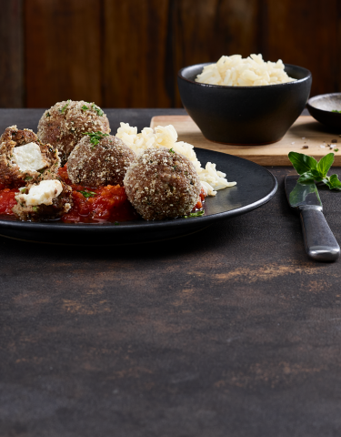 Hackbällchen auf einem Teller mit Feta und Tomatensauce